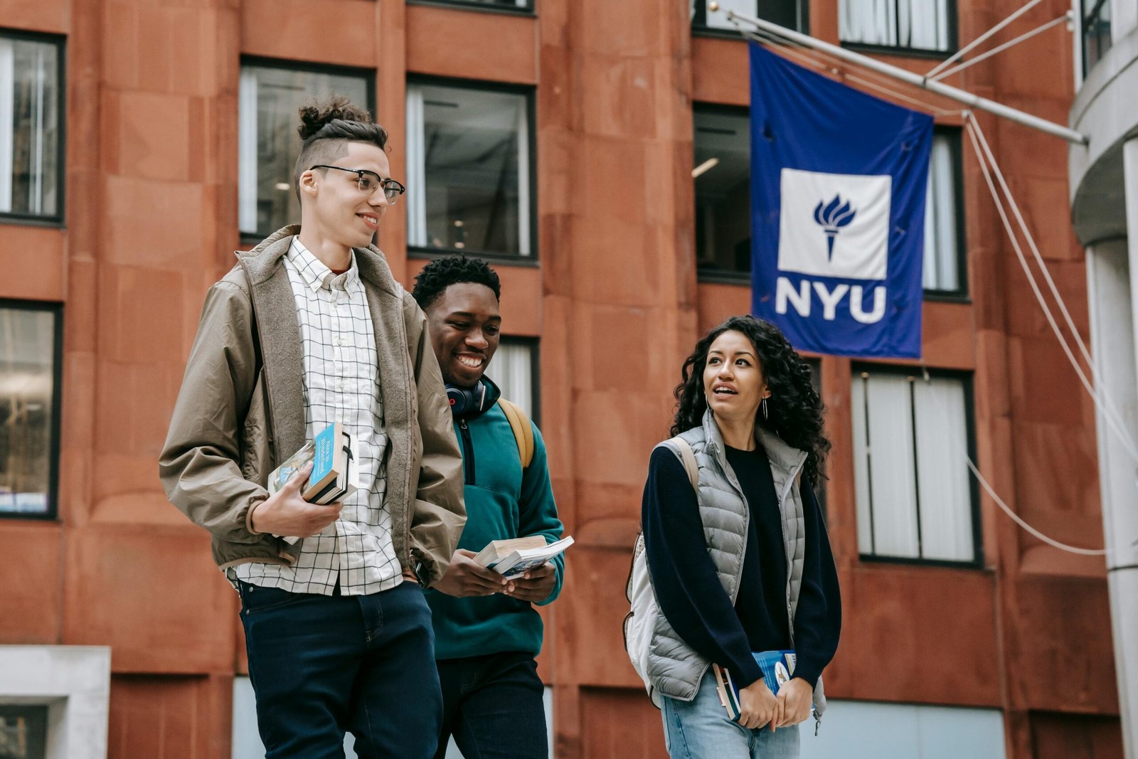 Group of diverse students chatting and smiling while walking on a university campus.